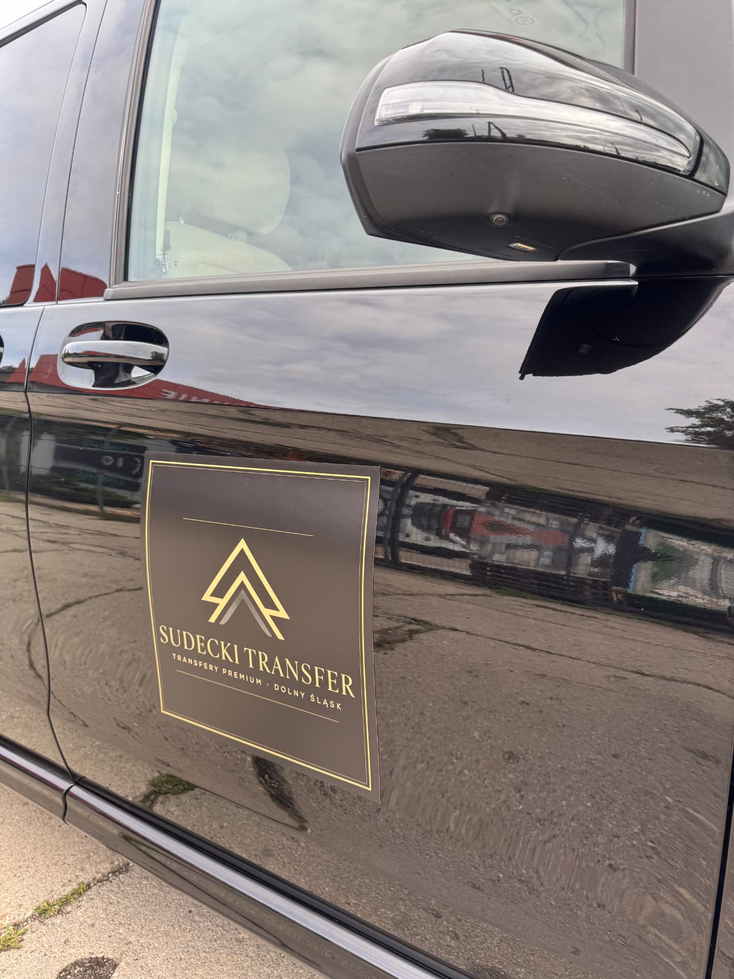 Złote logo Sudecki Transfer na drzwiach czarnego Mercedesa klasy V